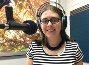 Image shows radio reading volunteer Emma Ross next to microphone in Vision Australia Radio's Perth studio
