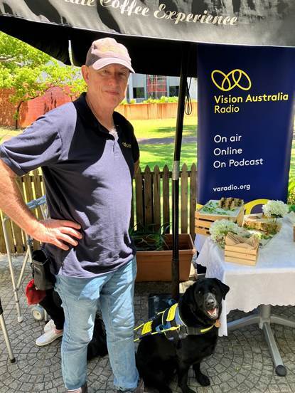 A middle-aged man stands beside a yellow labrador Seeing Eye Dog