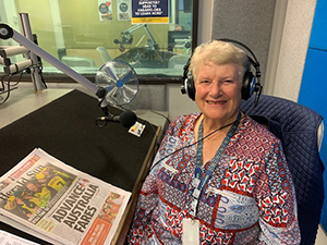 Volunteer in the studio, reading the newspaper on air.