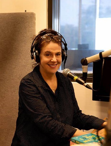 Fraces Keyland sitting at a microphone at the Vision Australia Radio offices, recording an episode of Hear This