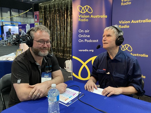 A picture of Will Crowe (left) being interviewed by Peter Greco (right).  They are seated in front of a Vision Australia Radio banner.