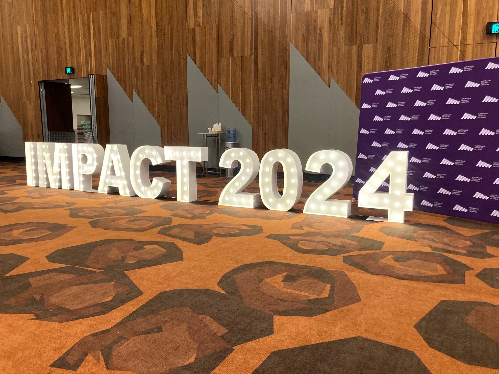 large light up white lettering sits on the floor of the exhibition hall spelling out ‘Impact 2024’.