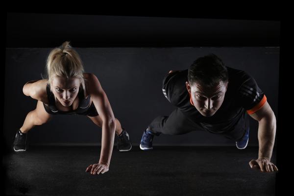 Photo of a man and woman in active wear doing one handed push-ups