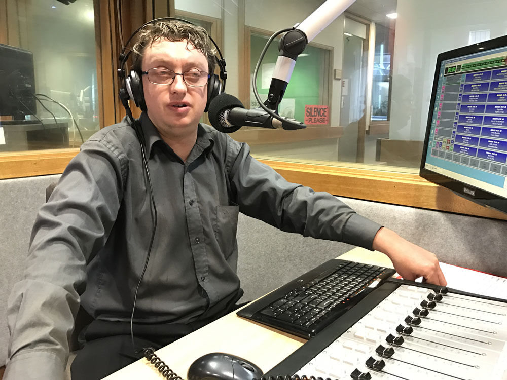 Matt sits at a radio mixing desk