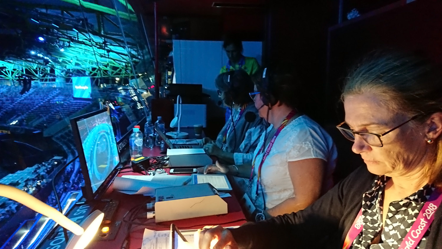 Three women doing audio description in a booth at the Sidney Myer Music Bowl