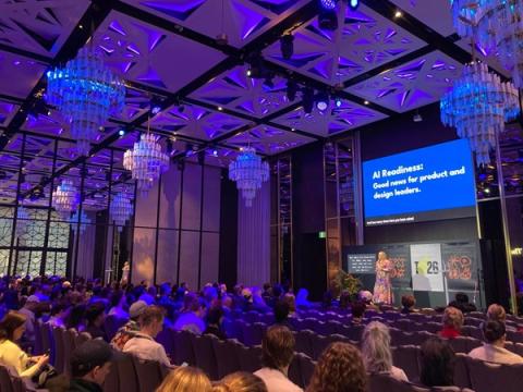 A lady wearing a long dress presenting on stage at The Outlook 2026 conference. 