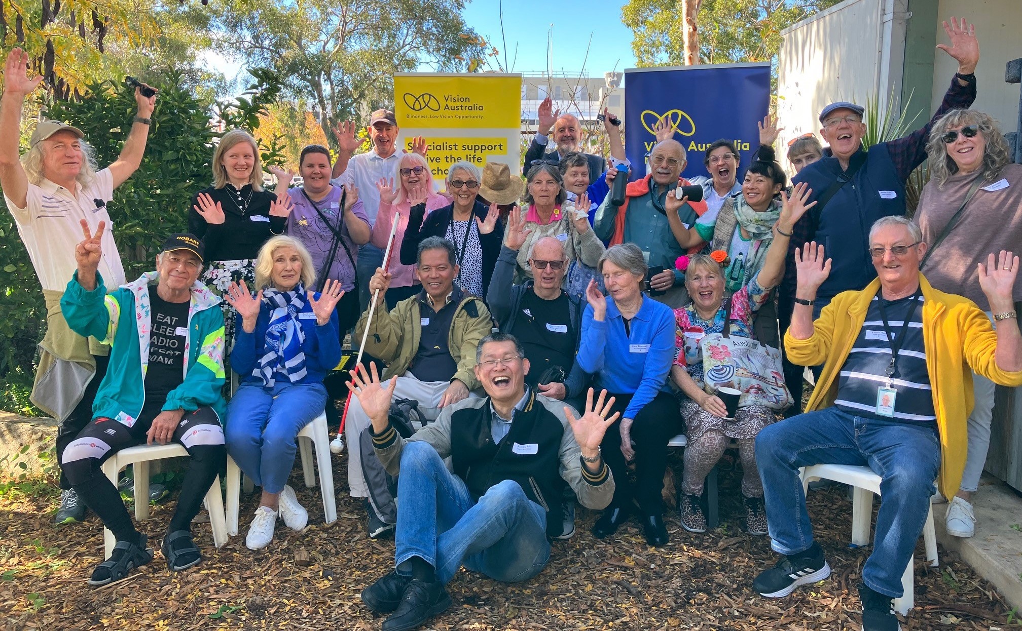 A group of volunteers are standing together with their hands raised in celebration